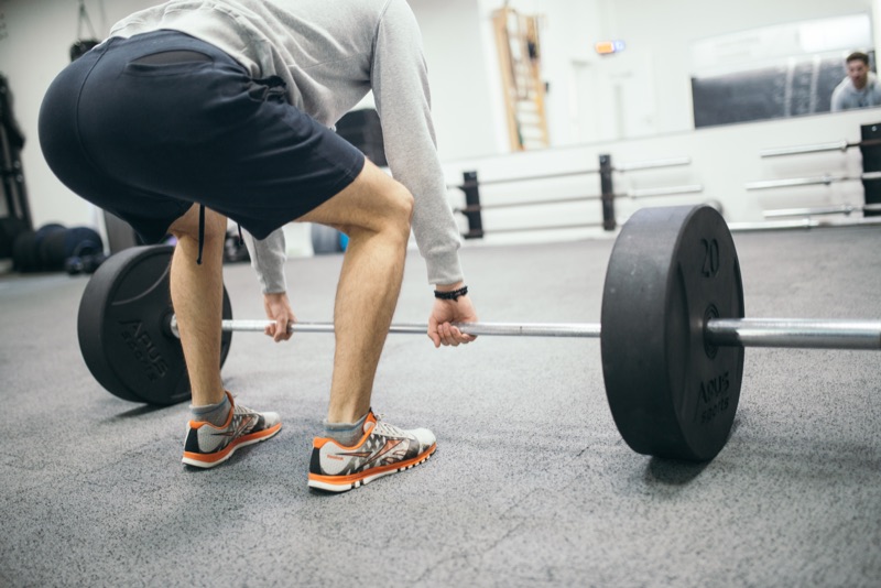 An athlete setting up a barbell deadlift in a gym