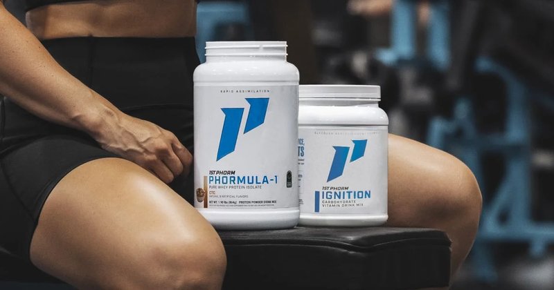 Tubs of 1st Phorm whey protein and Ignition on a gym bench