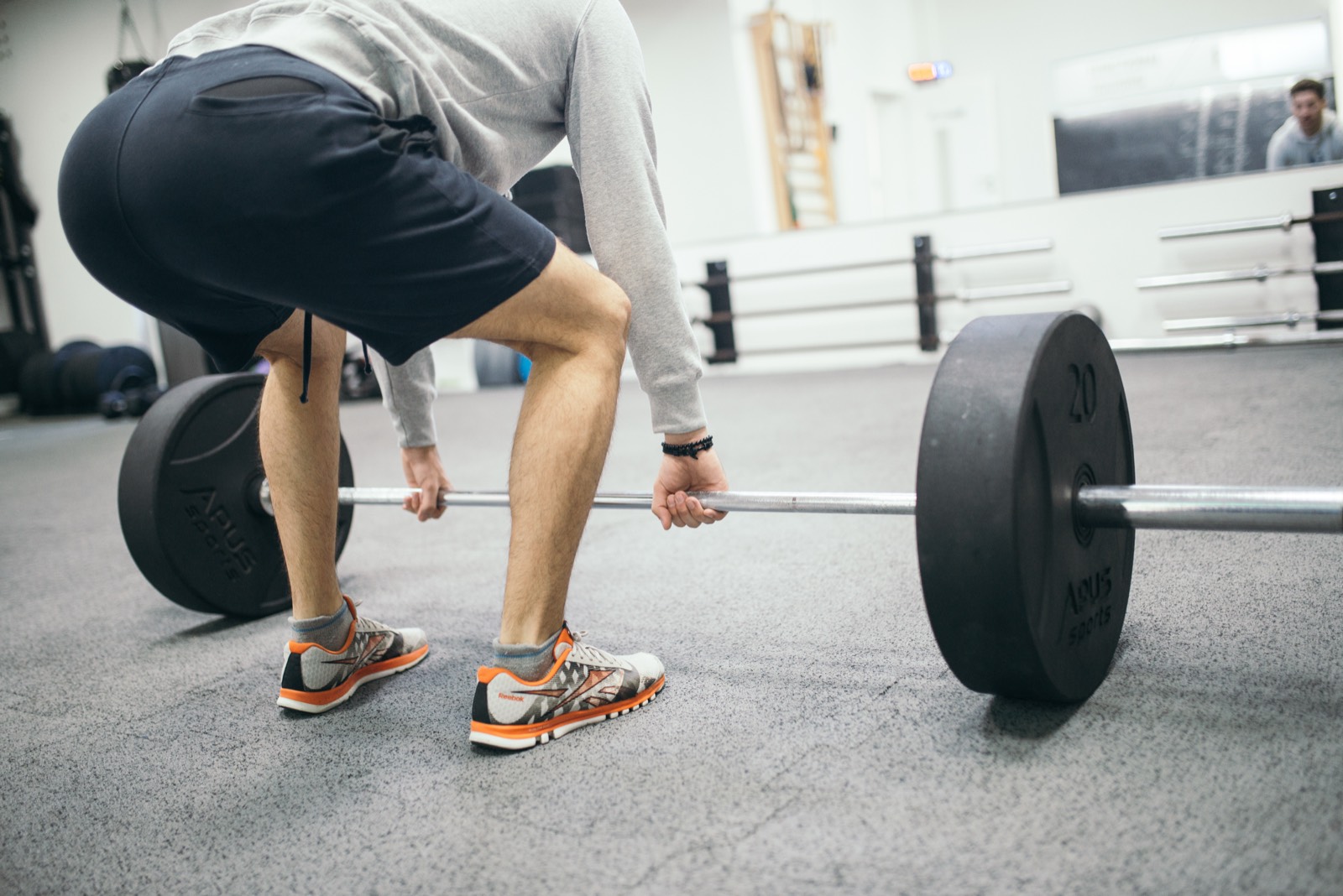 An athlete setting up a barbell deadlift in a gym — training that supplements support