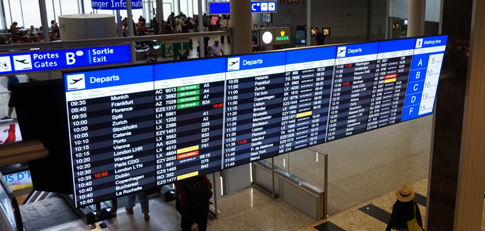 A large airport departure board listing flights and times at Geneva Airport