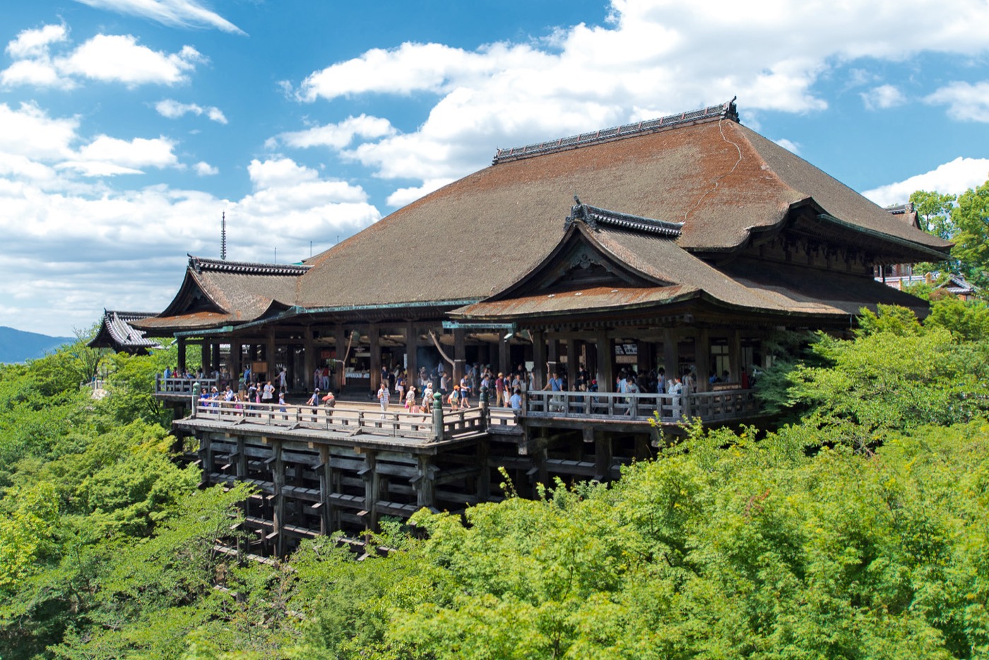 The wooden stage of Kiyomizu-dera temple built on stilts over a green hillside in Kyoto