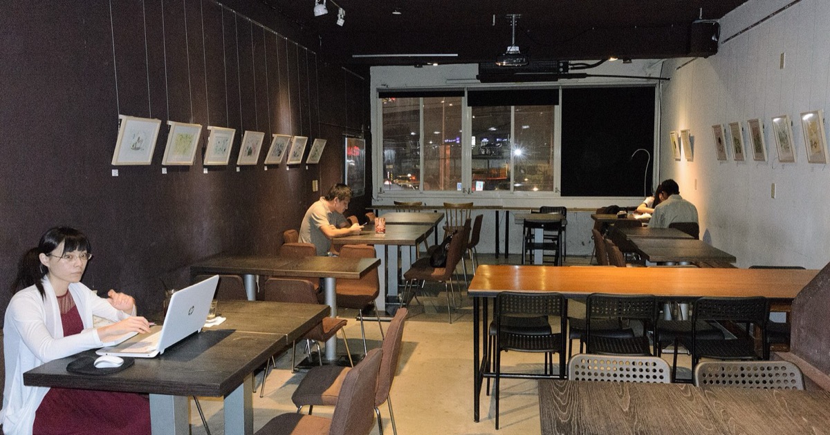 A quiet cafe interior with wooden tables and chairs, the kind of public wifi spot travellers work from